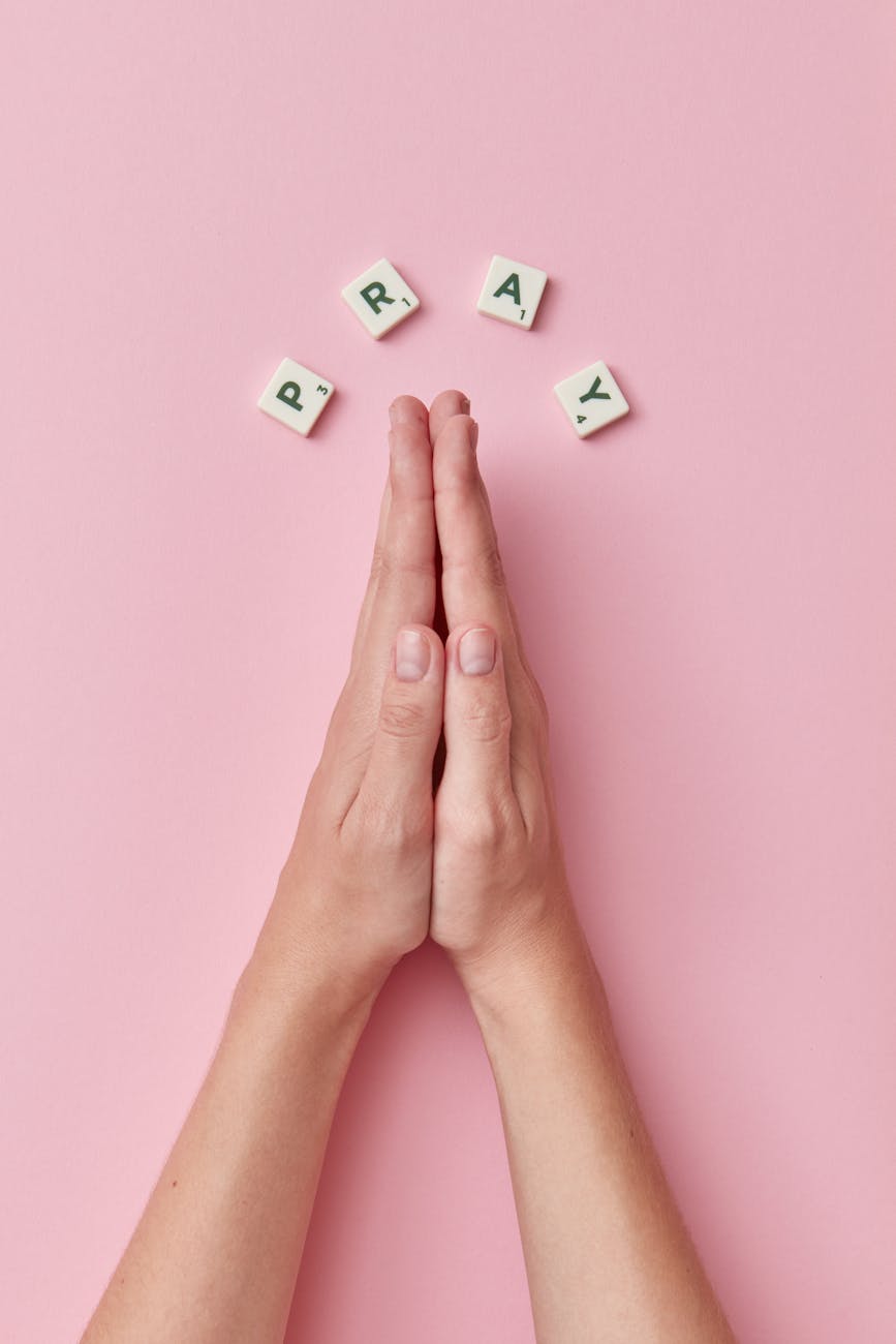 person in praying hands on pink surface