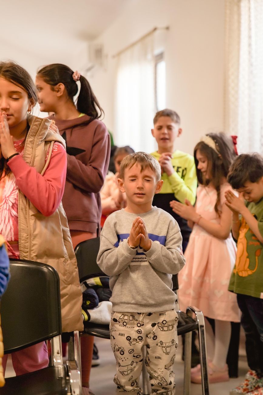 group of children in prayer at indoor event